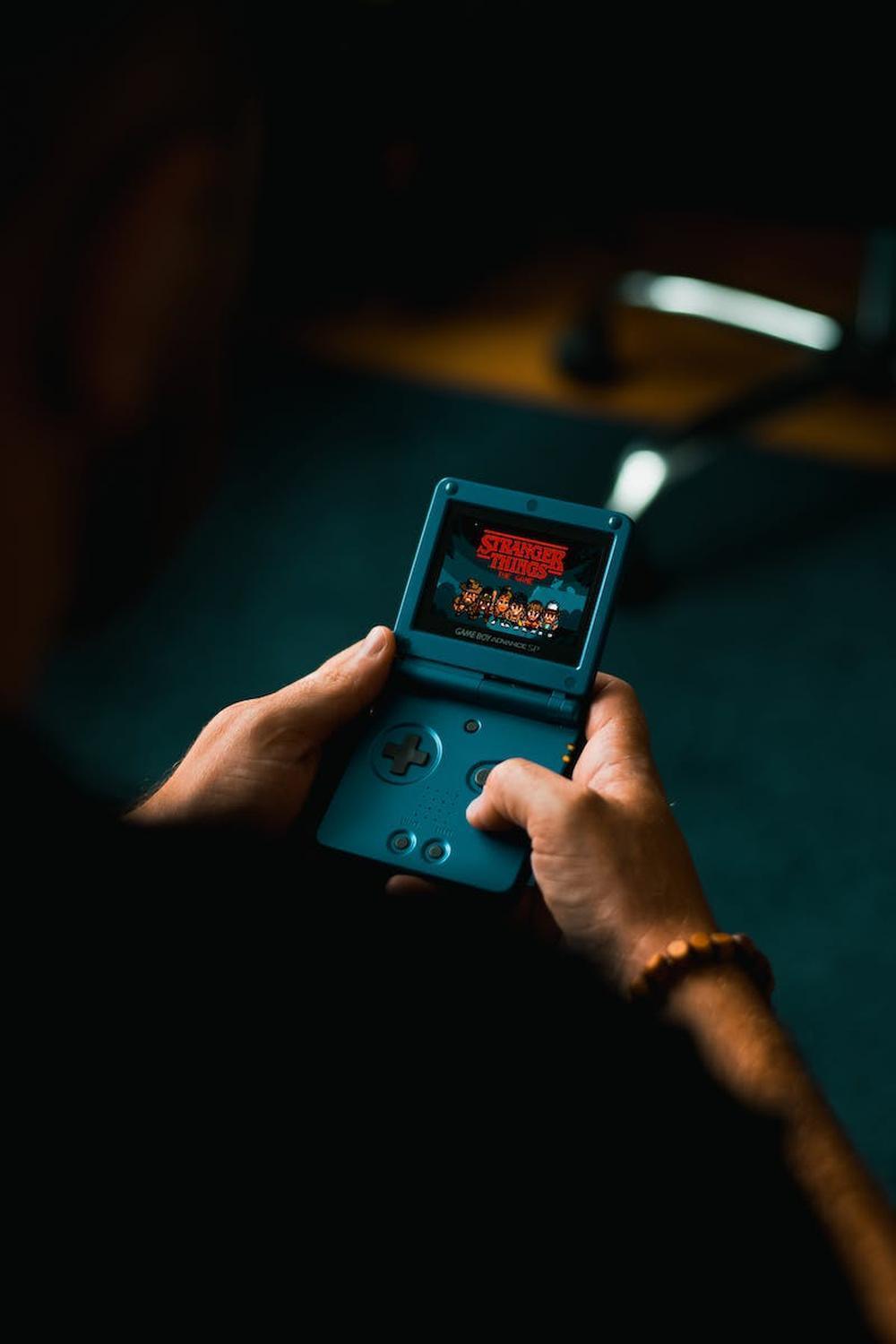 person_playing_with_handheld_game_console