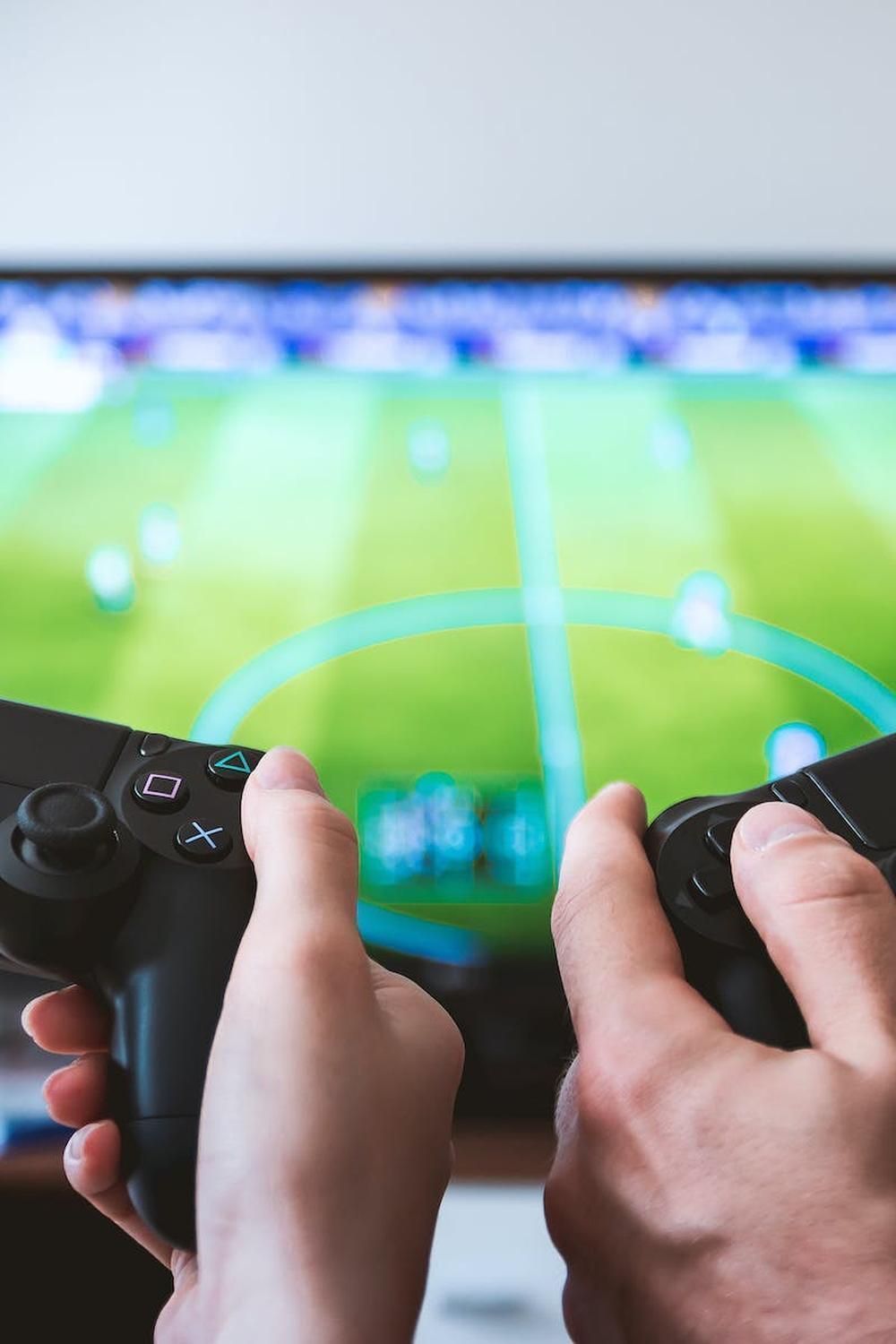 two_people_holding_black_gaming_consoles